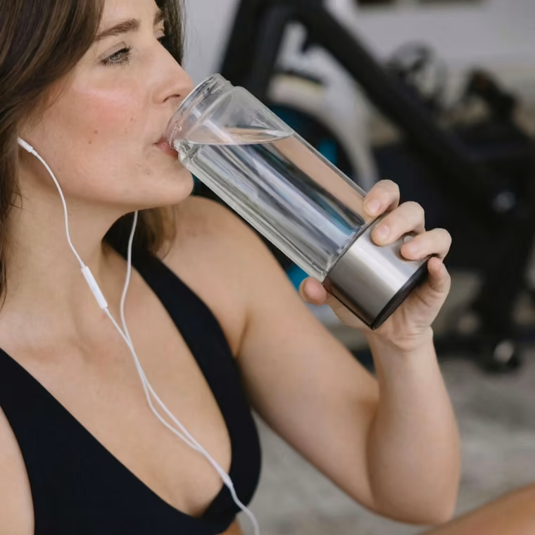 Donna che beve acqua idrogenata Aquivor durante il suo allenamento